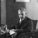 Florenz Ziegfeld reads behind a desk, 1930