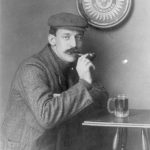 Man drinking a mug of beer under a Pabst - Milwaukee sign around 1900
